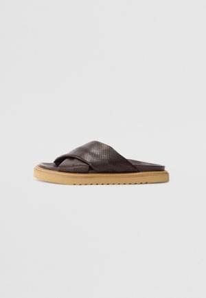 Brown leather slide sandals with textured cross straps, a flat sole, and a rubber bottom in a light tan color.