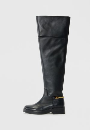 Zwarte leren laarzen tot boven de knie met een strak design, ronde neus, lage platformzool en gouden accenten bij de enkel.