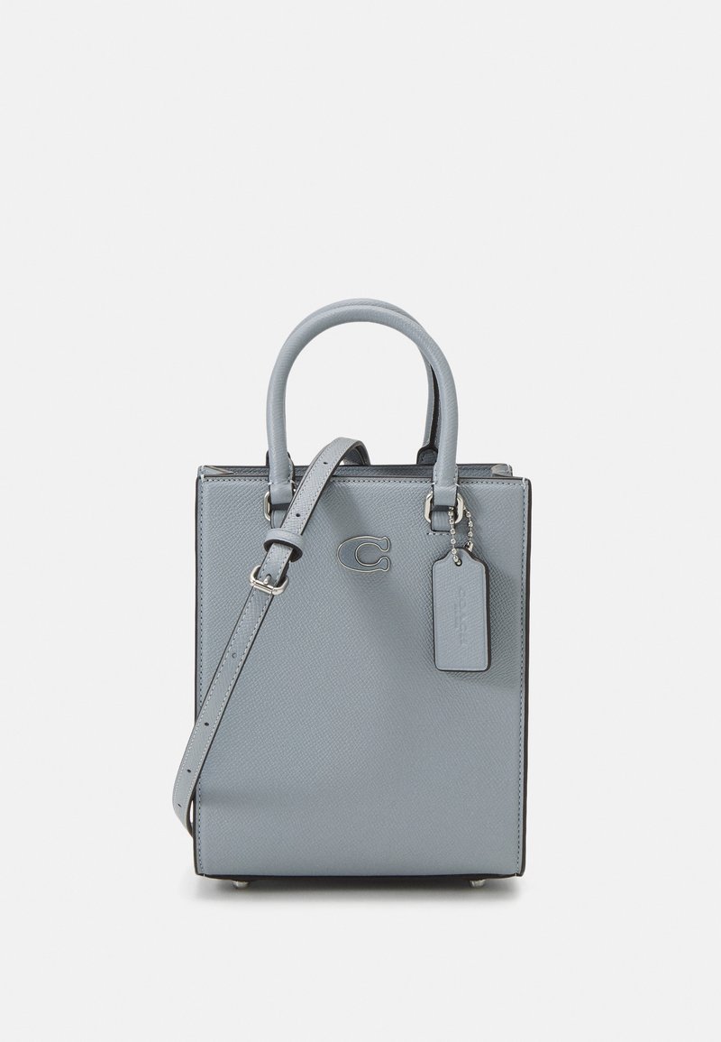 Petit sac rectangulaire en cuir texturé bleu clair avec deux poignées supérieures et une bandoulière détachable ; accent notable du logo.