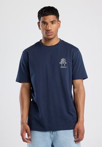 Camiseta de algodón azul marino con mangas cortas, escote redondo y pequeño diseño gráfico blanco en el pecho. Textura suave y corte relajado.