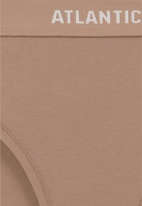 Beżowe bawełniane majtki o gładkiej fakturze. Posiadają biały napis "ATLANTIC" na gumce i bezszwową konstrukcję dla komfortu.