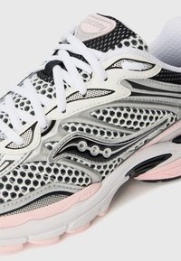 White and pink running shoe with mesh upper, featuring black accents, unique wave design, and three circular details near the midsole.