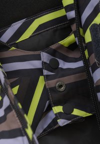 Mångfärgad innertyg med zigzag och randiga mönster i svart, gult och brunt; har svarta knappar och dekorativ snapsäkerhet.