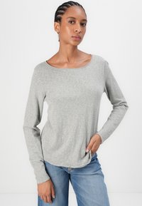 Gray long-sleeve shirt with a wide neckline, soft fabric, and a relaxed fit, paired with blue denim jeans. Smooth texture and casual design.