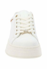 Zapatilla blanca con parte superior de lona texturizada, punta redonda y suela plana. Presenta ojales en tono dorado y herrajes decorativos para los cordones.