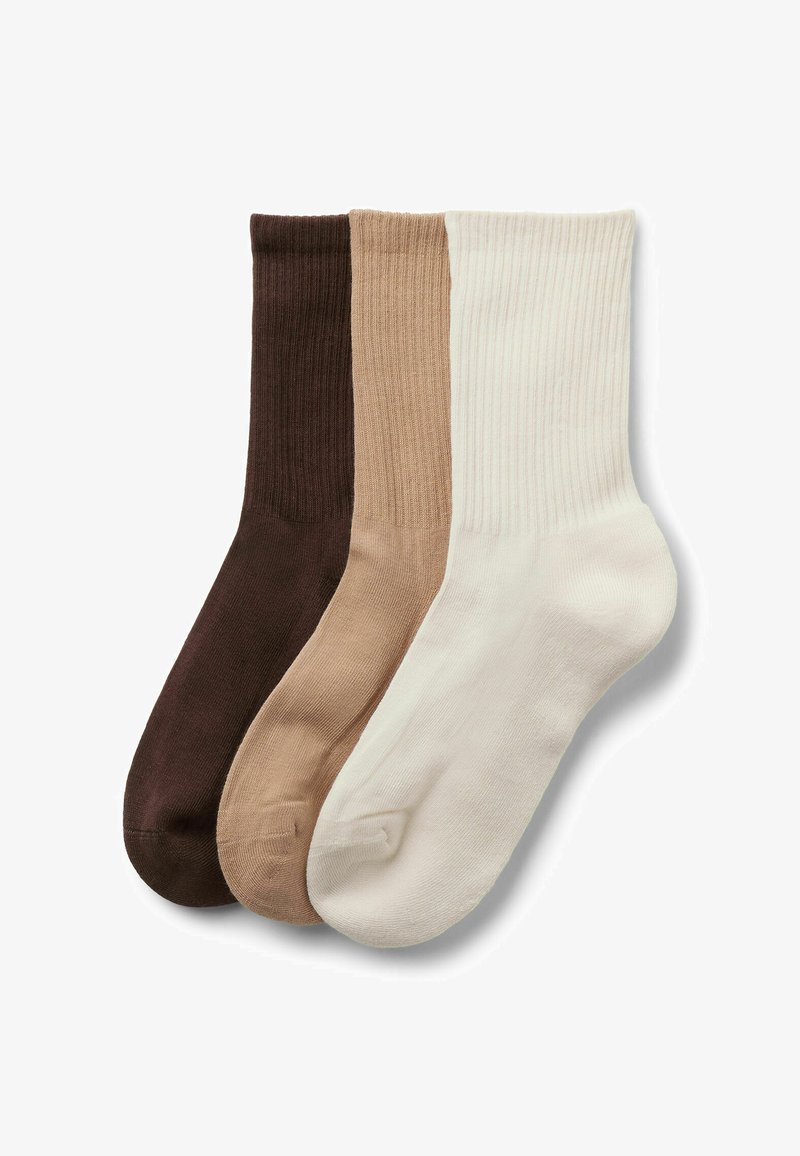 Trois chaussettes montantes côtelées en marron foncé, beige et blanc cassé, disposées côte à côte avec les orteils pointant vers la droite sur un fond blanc.