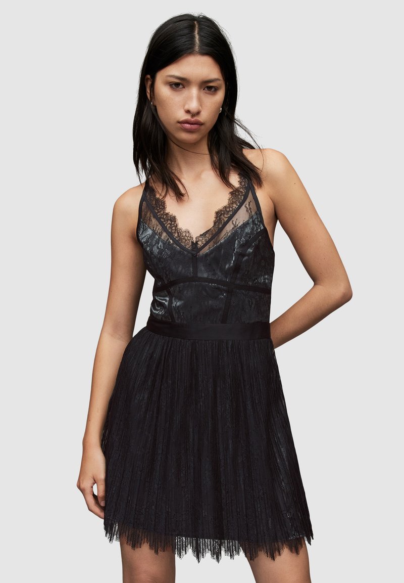 Schwarzes Kleid mit Spitzenakzenten, tailliertem Oberteil, dünnen Trägern und einem ausgestellten Rock. Die Textur ist glatt mit einem durchsichtigen Spitzenüberzug am Oberteil.