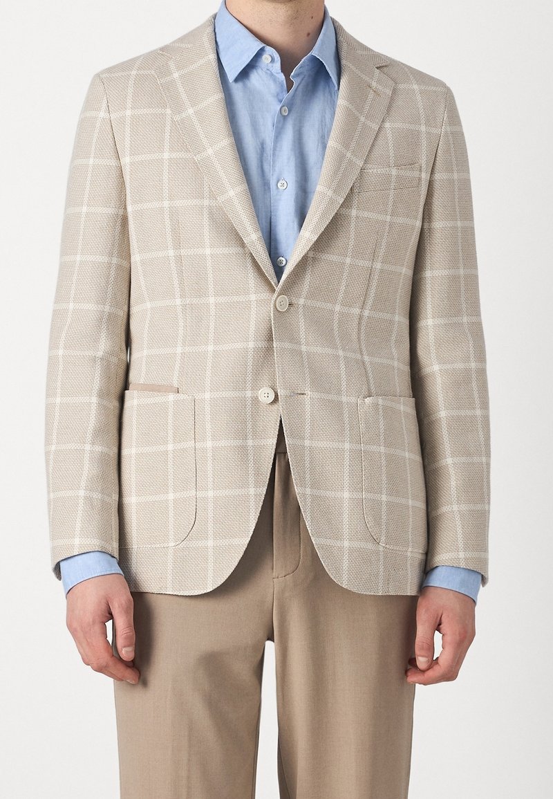 Beżowa marynarka w kratę z wzorem, z fakturowanym materiałem, dwoma przednimi kieszeniami i dwoma guzikami, zestawiona z jasnoniebieską koszulą.