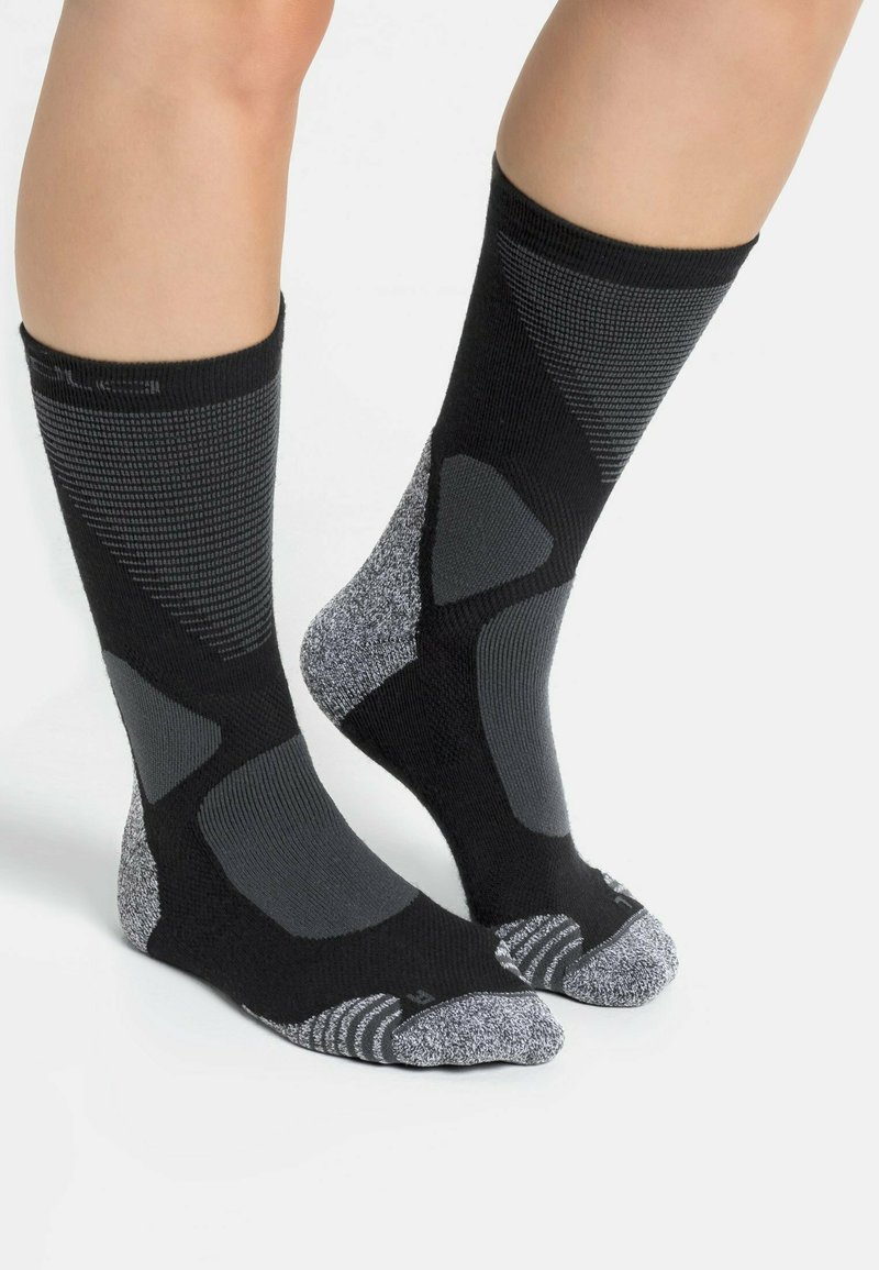 Chaussettes de sport noires et grises avec un design texturé, des zones de pied et de talon rembourrées, et des accents gris contrastants.