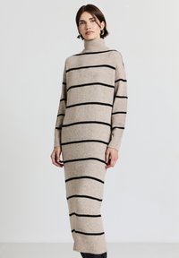 Abito in maglia beige con strisce orizzontali nere, collo alto, maniche lunghe e polsini a coste. Design aderente con lunghezza midi.