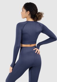Navyblaues, langärmliges Workout-Crop-Top mit tailliertem Design, weichem Textil und flachen Nähten, kombiniert mit passenden, hochtaillierten Leggings.