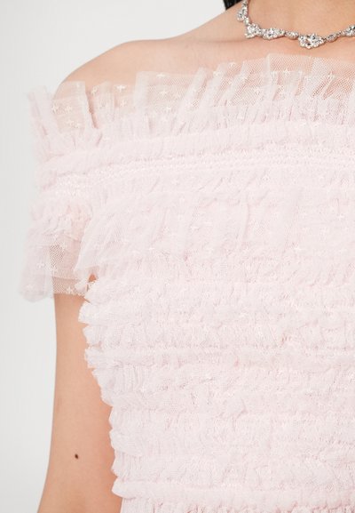 Pink off-shoulder top lavet af tekstureret tyl med flæsedetaljer. Har delikate stjernemønstre og et smockbånd lige under flæserne.