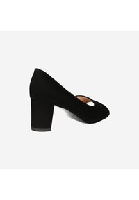 Black suede high-heeled shoe with a round toe and cut-out detail, featuring a chunky heel for added stability. Smooth texture with a minimal design.