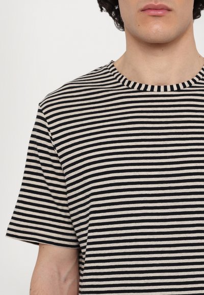 Tricou cu dungi în nuanțe de bej și negru, având un guler rotund, mâneci scurte și un material din bumbac moale, texturat.