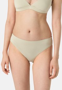 Slip bikini beige realizzato in tessuto morbido, con una trama liscia e un design a vita media. Taglio semplice senza motivi o hardware visibili.