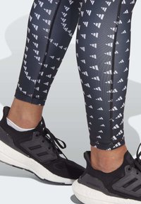 Zwart-wit gestreepte leggings met een geometrisch ontwerp en een elastische tailleband, gecombineerd met zwarte sport sneakers met een gestructureerde zool.