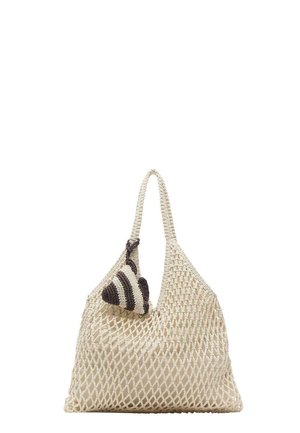 Beige geweven nettas met een enkele hengsel en een klein zwart-wit gestreept gehaakt accessoire eraan bevestigd.