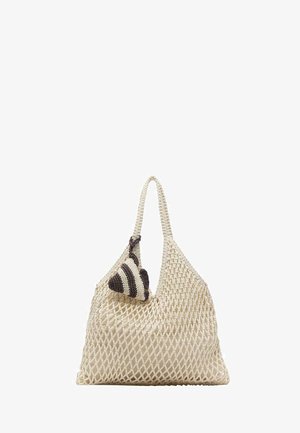 Geantă tote bej din plasă împletită, cu o singură mâner și o mică accesoriu croșetat în dungi alb-negru atașat.