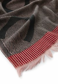 Écharpe tissée en motif carreaux noir et rose, avec des bords rayés rouges et des franges. Le matériau semble doux avec une finition texturée.