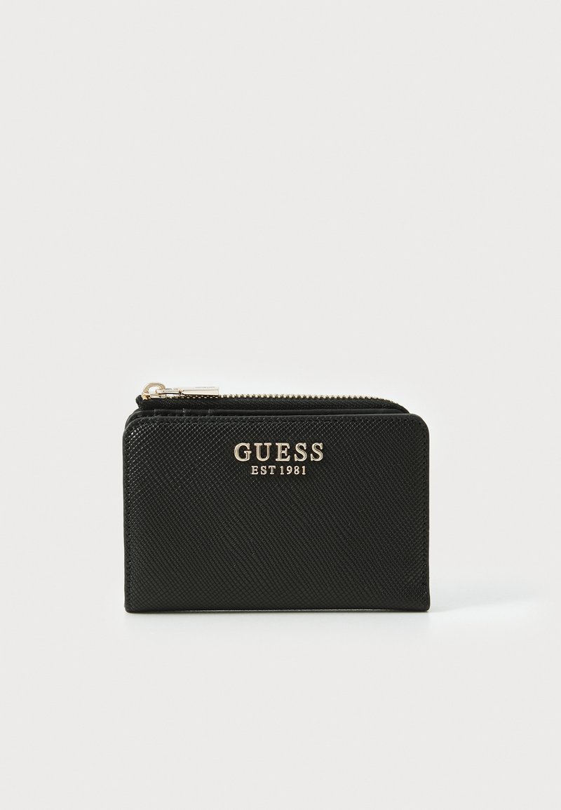 Portafoglio nero realizzato in materiale sintetico testurizzato. Presenta una chiusura con zip e un logo dorato con la scritta "GUESS EST 1981" sulla parte anteriore.