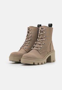 Tan leather ankle boots with a chunky heel, round toe, lace-up front, side zipper, and textured rubber sole.