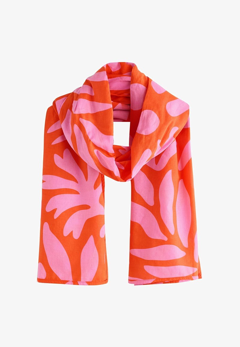 Écharpe orange avec de grands motifs abstraits de feuilles roses, pliée de manière lâche avec les extrémités pendantes.