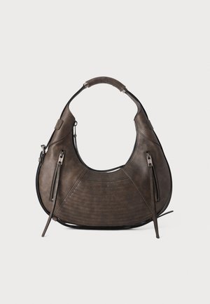 Sac à main en cuir brun foncé en forme de croissant avec deux poches verticales zippées et une poignée rembourrée.
