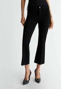 Jeans svasati in denim nero con vita media e cinque tasche, caratterizzati da cuciture sottili e chiusura con bottone.