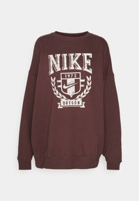 Vinröd Nike-tröja med vintage-inspirerat tryck som inkluderar "Nike", "1972", en sköld och lagerkransdetaljer i vitt. Långärmad med rund hals.