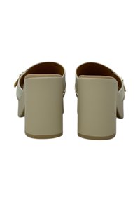 Mule con tacco in pelle nuda, con punta quadrata e tacco a blocco chunky. Presentano una fibbia laterale e una finitura liscia.