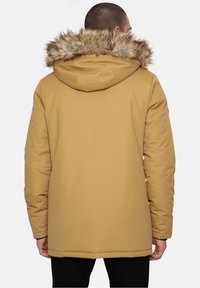 Bruine geïsoleerde parka met afneembare capuchon van nep bont, stevig materiaal, lange mouwen en een ontspannen pasvorm. Zichtbare stiksels en zijzakken.