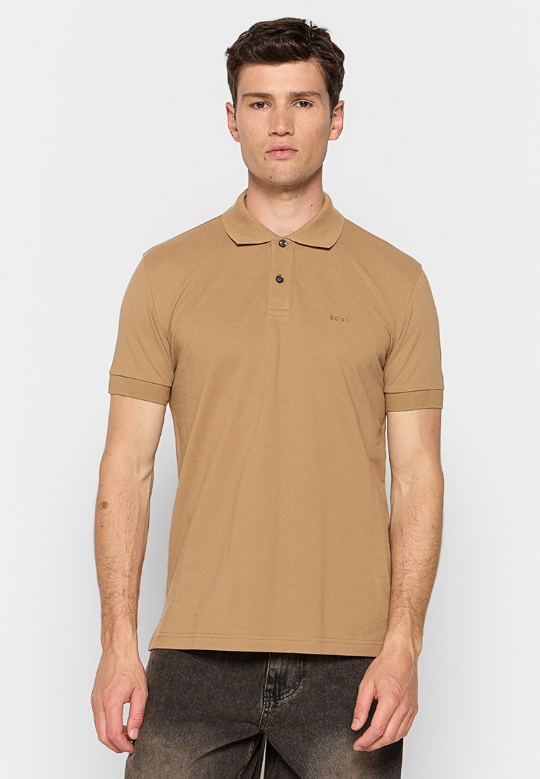 Polo shirt marron en tissu lisse, avec un col classique, une patte de boutonnage à deux boutons et des manchons courts. Logo brodé sur la poitrine.