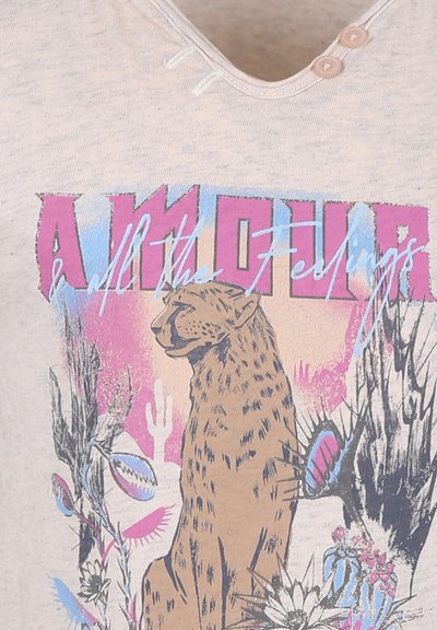 Beige t-shirt met een grafisch ontwerp van een luipaard, omringd door cactussen en bloemen, met de tekst "AMOUR & alle Gevoelens" in felle kleuren.