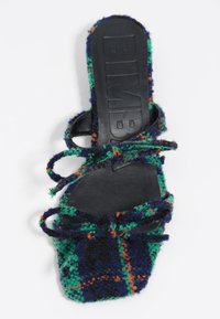 Sandalia tipo chancla de tela a cuadros verdes y azul marino con plantilla de cuero negro y cordones. Textura suave con diseño plano y punta abierta.