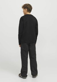 Svart sweatshirt med långa ärmar, rundad halsringning och strukturerad tyg, tillsammans med svarta cargobyxor med sidfickor och avslappnad passform.