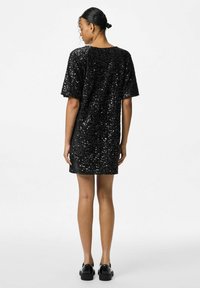 Melnas secinētās kleitas īsām piedurknēm, brīvā fitā un ar apaļu kakla izgriezumu, ar gludu tekstūru un spīdīgām akcentiem.