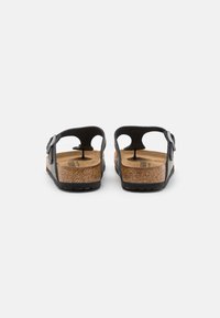Black sandals with cork footbed and rubber sole, featuring a back strap and adjustable buckle, designed for comfort and durability.