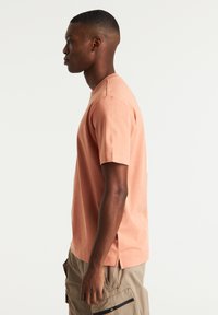 T-shirt a maniche corte in un morbido colore pesca, realizzato in un misto di cotone, con un fit rilassato e fessure laterali all'orlo.