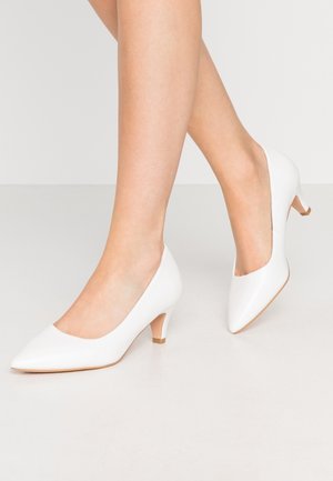 Escarpins blancs en cuir avec un bout pointu et un petit talon carré. Texture lisse avec un design minimaliste, adaptés pour une tenue formelle.