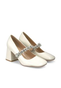 Chaussures à talon carré en cuir verni blanc avec un bout carré et une sangle décorative ornée de cristaux sur le cou-de-pied.