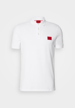Hvit polo-skjorte laget av bomull, med en placket med tre knapper, korte ermer og et rød rektangulært logo-patch på venstre bryst.