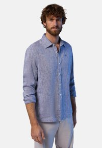 Camicia a maniche lunghe in lino azzurro chiaro con colletto, chiusura frontale a bottoni e maniche arrotolate; presenta una sottile trama e un logo sul petto.