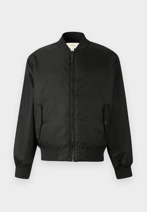 Chaqueta bomber negra con cremallera frontal, cuello, puños y dobladillo acanalados, y dos bolsillos con solapa y botones a presión.