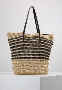 Velká tkaná taška z přírodního slámy s černými pruhovanými akcenty. Disponuje dvěma černými uchy a otevřeným vrškem.