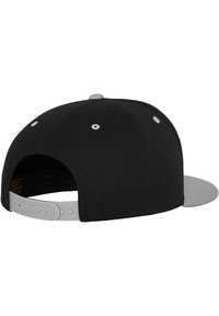 Čierna čiapka s šedým plochým okrajom, s bielymi očkami a nastaviteľným snapback uzáverom na zadnej strane. Vyrobená z pevných materiálov.