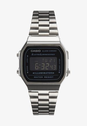 Digitální hodinky Casio se stříbrným nerezovým páskem. Černý ciferník zobrazuje čas a den, má boční tlačítka a je voděodolný.