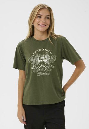 T-shirt en coton vert olive à manches courtes, avec un design graphique blanc de oiseaux et le texte "FLY TOO HIGH" et "Liberté."