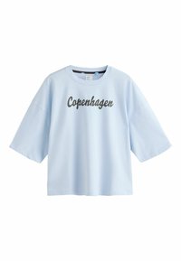 T-shirt oversize bleu clair avec « Copenhagen » écrit en écriture sombre sur la poitrine, avec un col rond et des manches courtes.