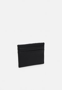 Porte-cartes en cuir noir avec une surface texturée, dotée de plusieurs emplacements pour cartes et d'une forme rectangulaire compacte.