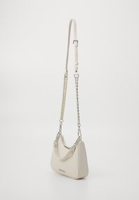 Beige læderhåndtaske med et bøjet design, justerbar læderrem og sølv- samt guld-kæde detaljer. Lynlåslukning i toppen.